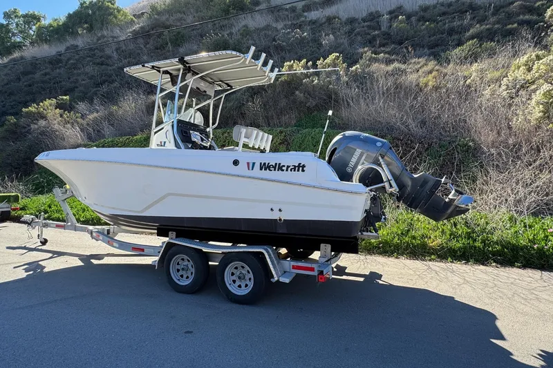 Slide: The Image of 2020 Wellcraft 222 Fisherman boat on trailer, parked on roadside with scenic background. - 7