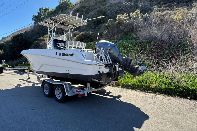 Slide: The Image of 2020 Wellcraft 222 Fisherman boat on trailer, parked near lush hillside. - 8