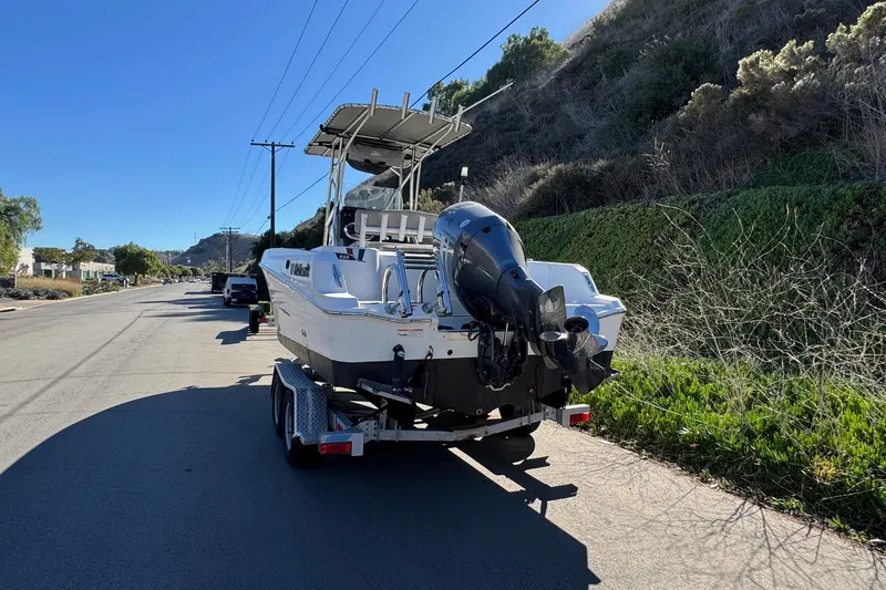 Slide: The Image of 2020 Wellcraft 222 Fisherman boat on trailer, parked roadside under clear blue sky. - 9