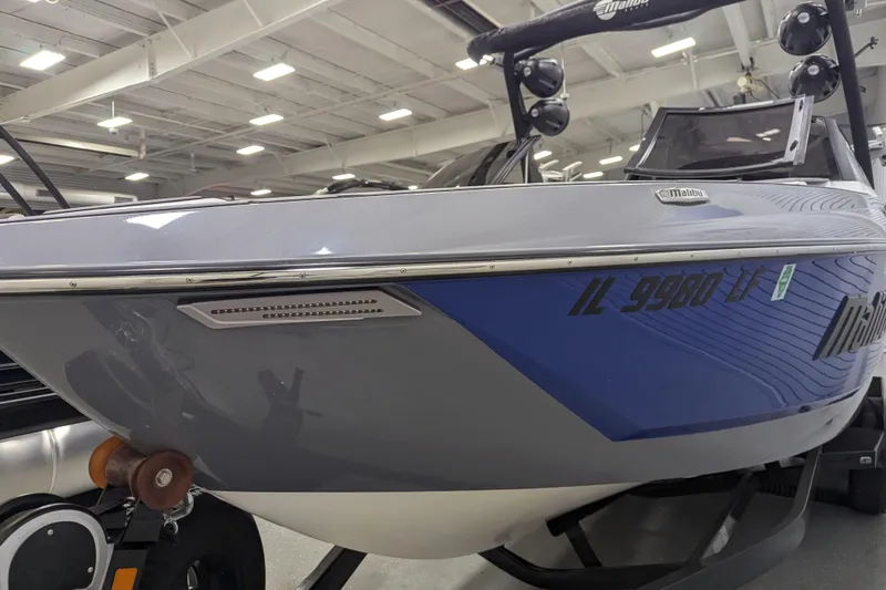 Slide: The Image of 2023 Malibu Wakesetter 25 LSV boat in showroom, sleek design, blue and gray exterior. - 17