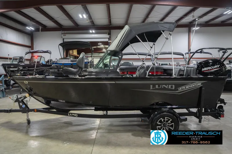 Slide: The Image of 2026 Lund 1675 Adventure Sport boat in showroom, featuring Mercury engine and canopy. - 11