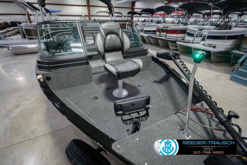 Slide: The Image of 2026 Lund 1675 Adventure Sport boat interior with seating and navigation equipment in showroom. - 13