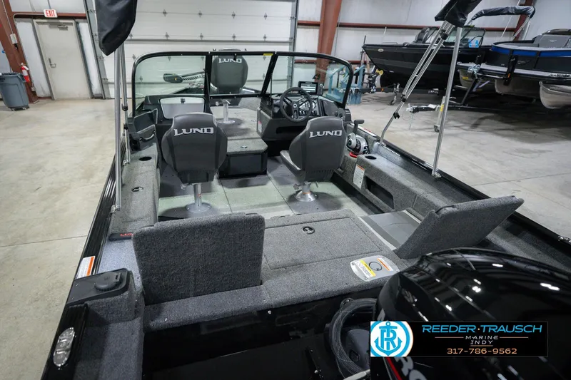 Slide: The Image of 2026 Lund 1675 Adventure Sport boat interior with seating and steering wheel in showroom. - 15