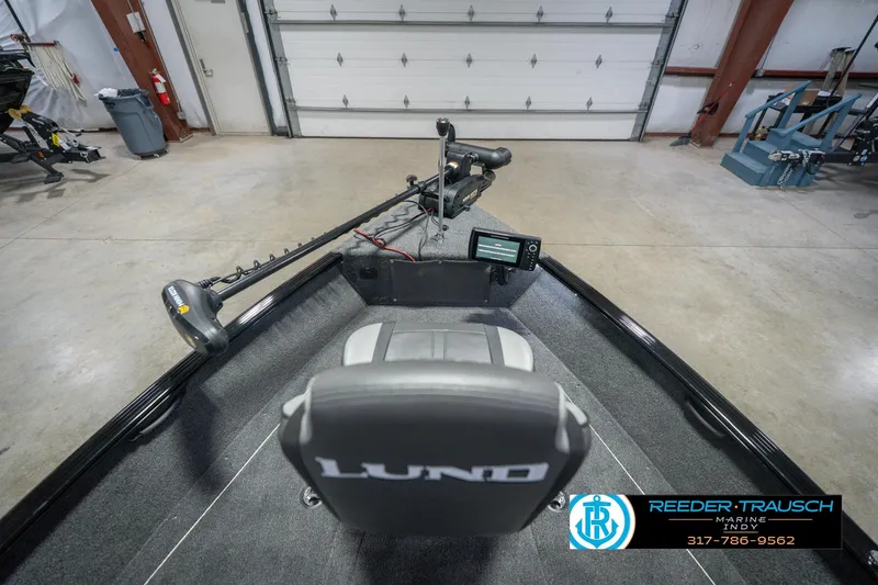 Slide: The Image of 2026 Lund 1675 Adventure Sport boat interior with steering console and trolling motor in a garage. - 18