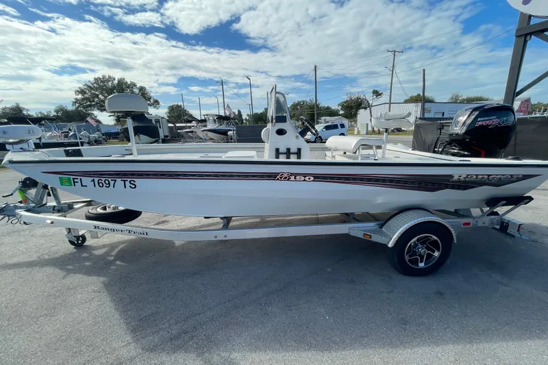Slide: The Image of 2023 Ranger RB190 boat on trailer, parked outdoors under a partly cloudy sky. - 7