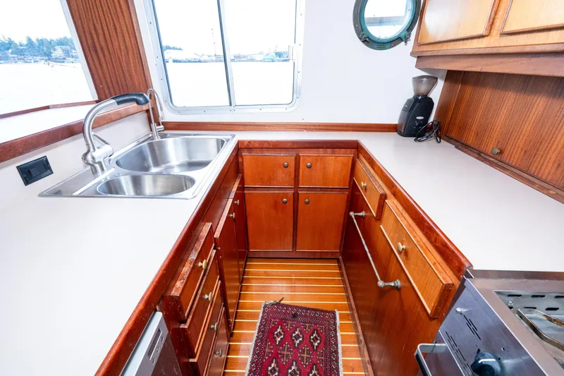 Slide: The Image of Wooden boat kitchen with double sink, cabinets, and window on a 1966 Willard Marine 47. - 19