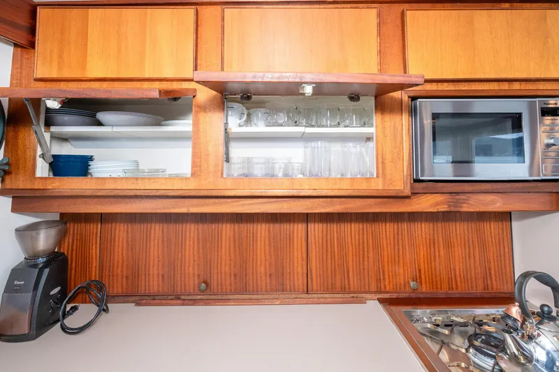 Slide: The Image of Wooden kitchen cabinets with open shelves, microwave, coffee grinder, and kettle on a 1966 Willard Marine 47. - 22
