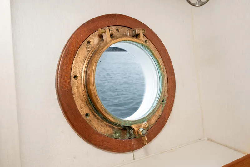 Slide: The Image of Vintage 1966 Willard Marine 47 porthole with brass and wood frame, overlooking the sea. - 52