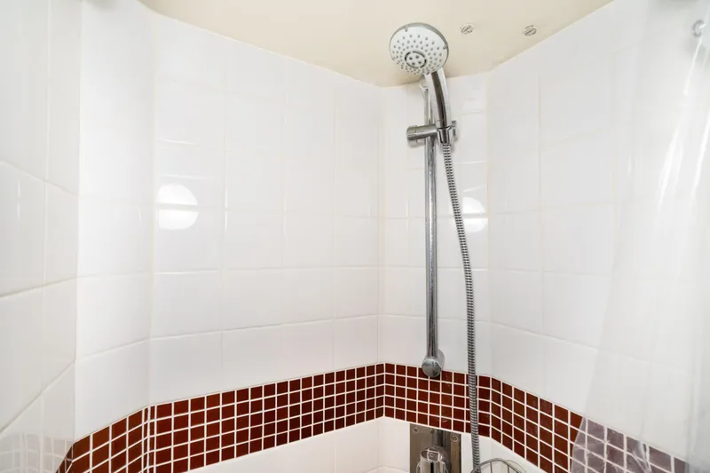 Slide: The Image of Shower area with white tiles and red mosaic accent, featuring a handheld showerhead. - 66