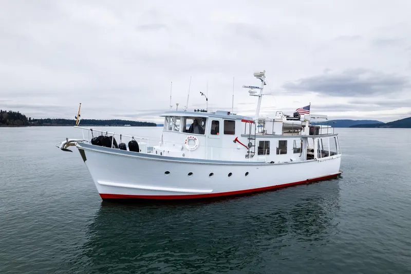 Slide: The Image of 1966 Willard Marine 47 boat on calm water, overcast sky, American flag displayed. - 68