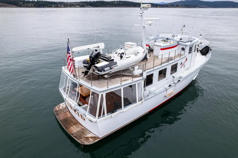 Slide: The Image of 1966 Willard Marine 47 yacht on calm water, featuring upper deck and American flag. - 71