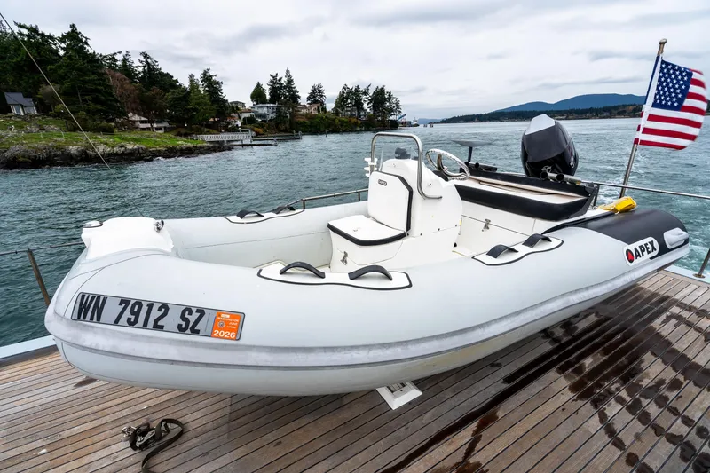Slide: The Image of Apex inflatable boat docked on a wooden deck, with American flag and scenic water view. - 80