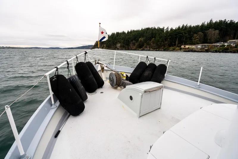 Slide: The Image of Bow of 1966 Willard Marine 47 boat with fenders, cruising near forested shoreline. - 83