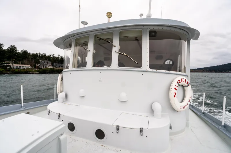 Slide: The Image of 1966 Willard Marine 47 boat on water, featuring cabin and lifebuoy, near shoreline. - 84