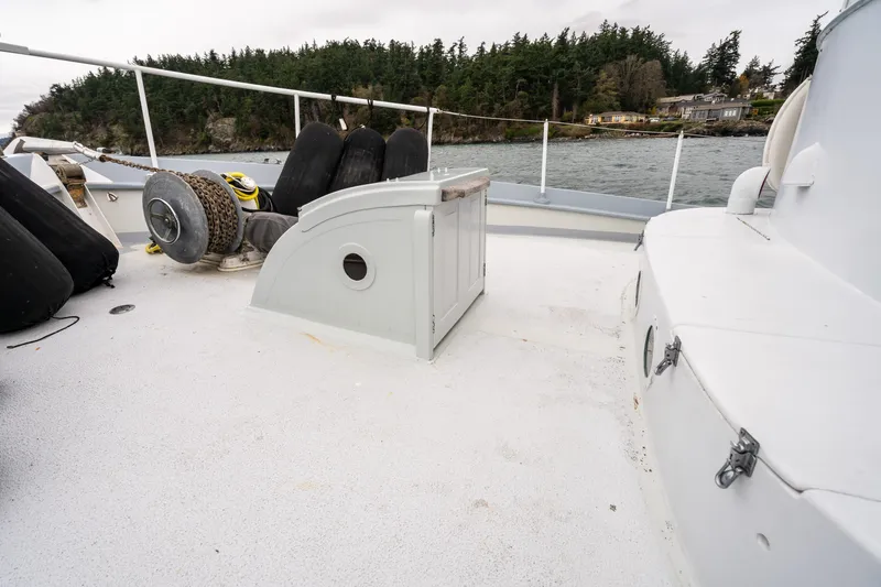 Slide: The Image of Deck of 1966 Willard Marine 47 boat with winch and fenders, near forested shoreline. - 85