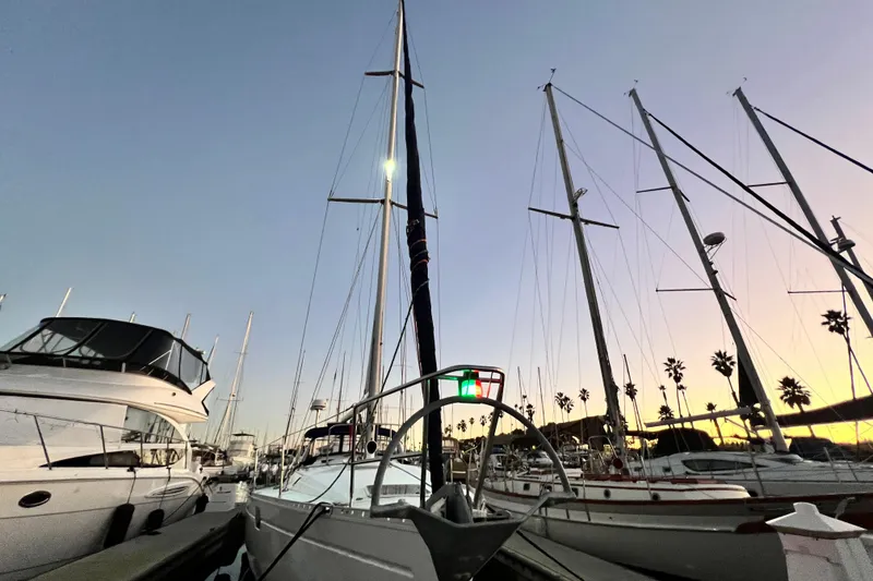 Slide: The Image of 1993 Beneteau Oceanis 440 sailboat docked at sunset, surrounded by other yachts. - 12