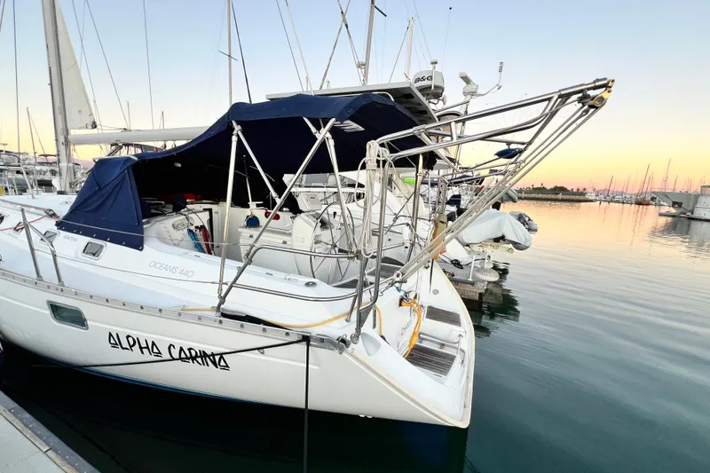 Slide: The Image of 1993 Beneteau Oceanis 440 sailboat docked at sunset, featuring sleek design and blue canopy. - 3