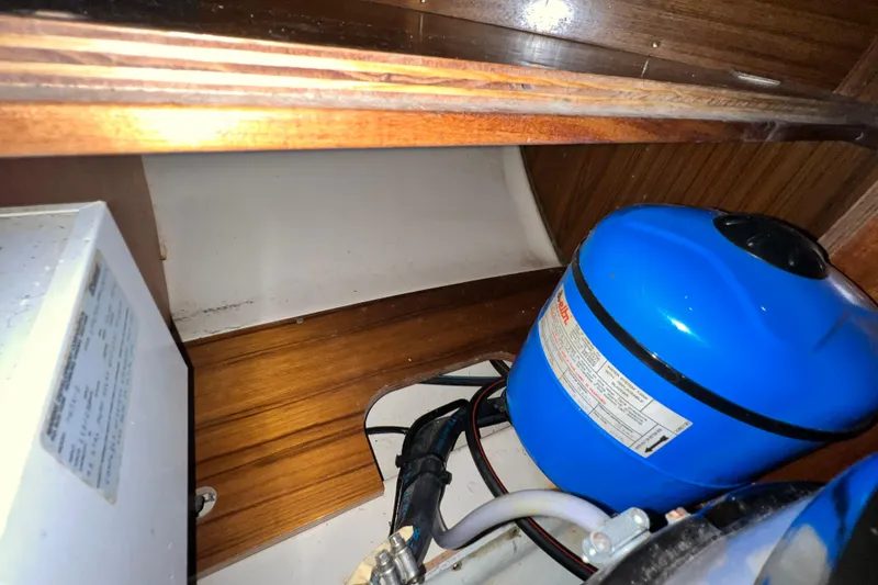 Slide: The Image of Interior of a 1993 Beneteau Oceanis 440 showing a blue water tank and wooden paneling. - 46