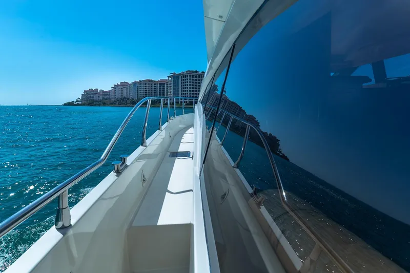 Slide: The Image of 2005 Marquis 59 yacht cruising near coastal buildings under clear blue sky. - 13
