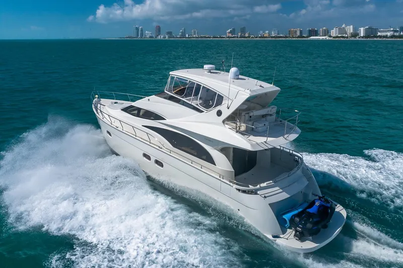 Slide: The Image of Luxurious 2005 Marquis 59 yacht cruising on turquoise waters near a city skyline. - 2