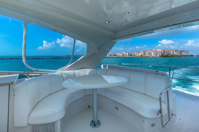 Slide: The Image of Luxurious 2005 Marquis 59 yacht interior with white seating, ocean view, and cityscape in the background. - 20