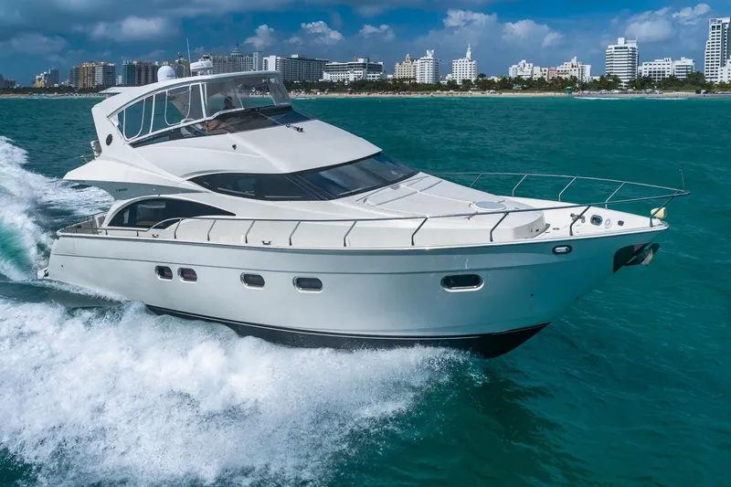 Slide: The Image of Luxury 2005 Marquis 59 yacht cruising in turquoise waters near a city skyline. - 3