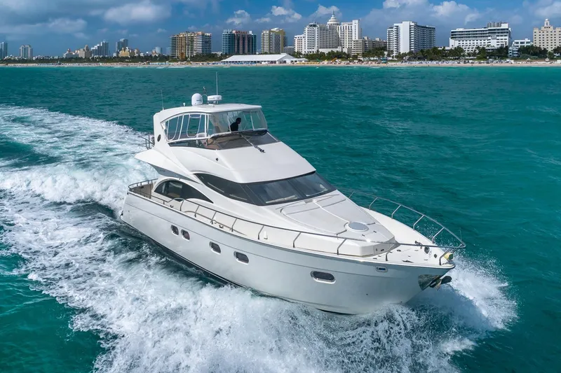 Slide: The Image of Luxury 2005 Marquis 59 yacht cruising near city skyline on turquoise waters. - 5