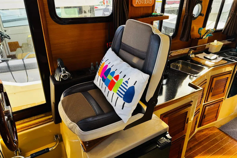 Slide: The Image of Captain's chair in 2012 Ranger Tugs R-31 boat interior with colorful pillow and wooden cabinetry. - 14