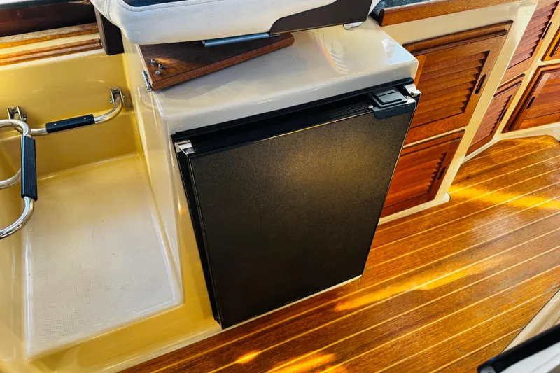 Slide: The Image of 2012 Ranger Tugs R-31 interior with wooden flooring and compact black refrigerator. - 18