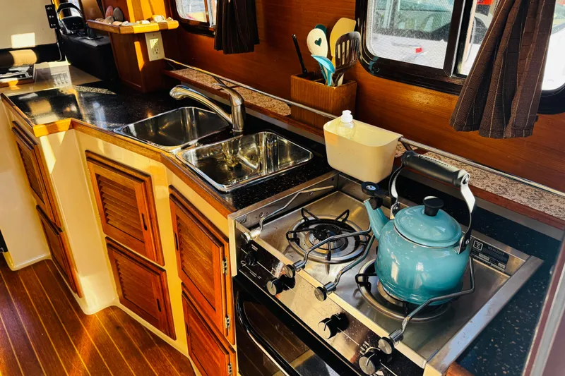 Slide: The Image of Cozy 2012 Ranger Tugs R-31 kitchen with stove, sink, and wooden cabinets. - 4