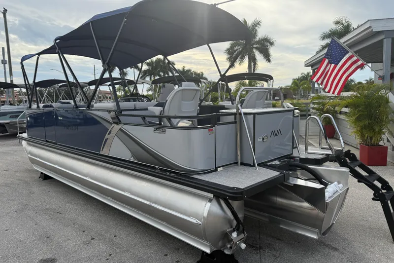 Slide: The Image of 2026 Avalon 2385 LSZ Rear Fish Tri Toon boat with American flag, parked outdoors. - 11