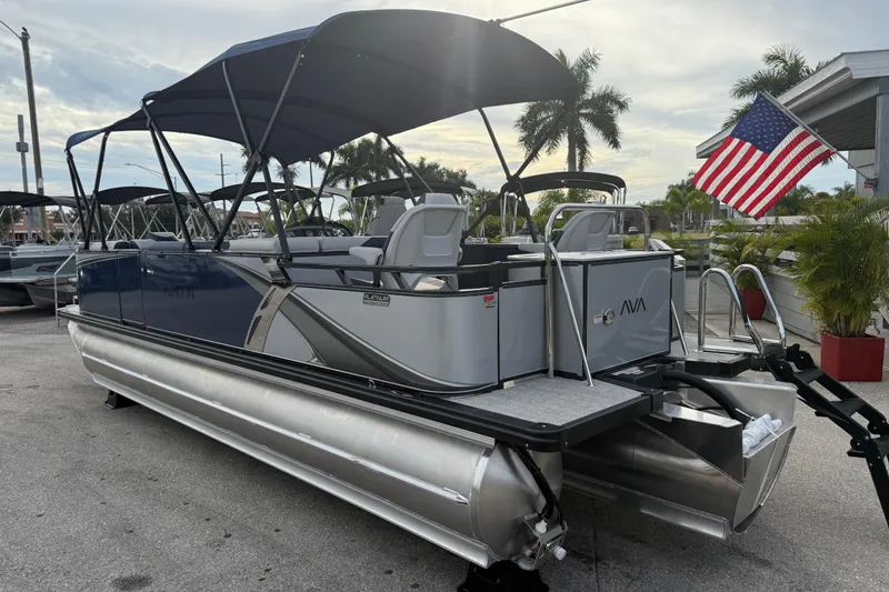 Slide: The Image of 2026 Avalon 2385 LSZ Rear Fish Tri Toon boat with American flag, parked outdoors. - 12