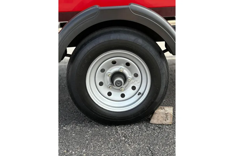 Slide: The Image of Trailer wheel of 2022 Bayliner Element M15 on asphalt with wooden block. - 14