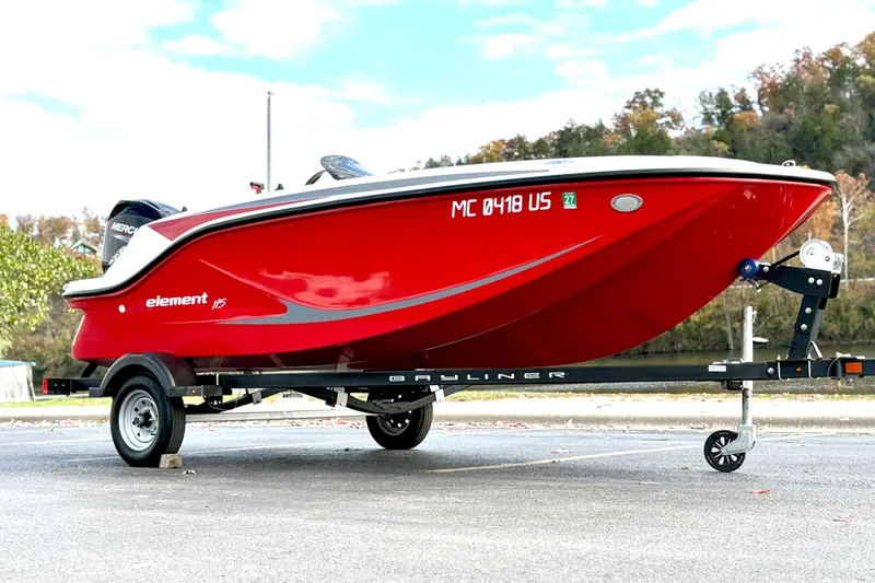 Slide: The Image of 2022 Bayliner Element M15 boat in vibrant red on a trailer, parked outdoors. - 3