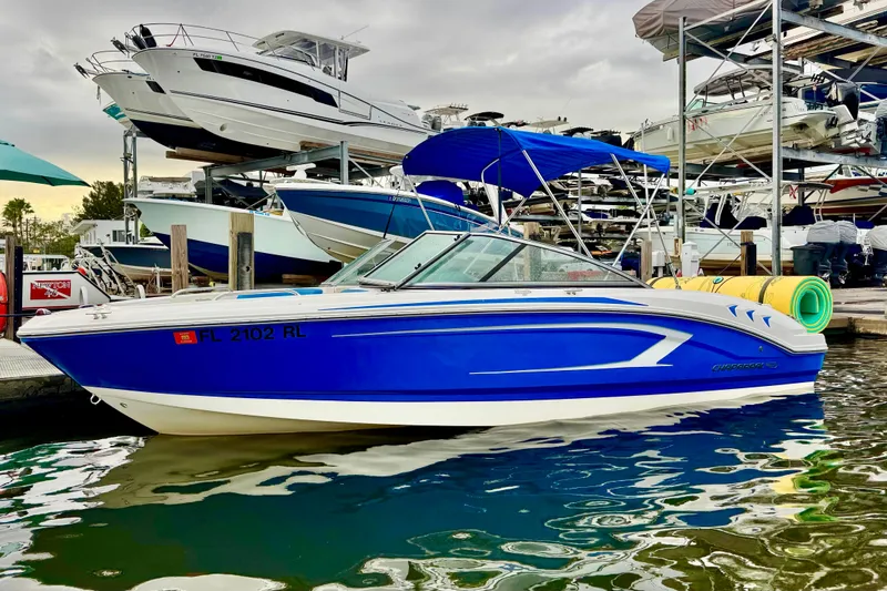 The Image of 2018 Chaparral 21 H2O Sport boat docked at marina, blue and white design. - 0