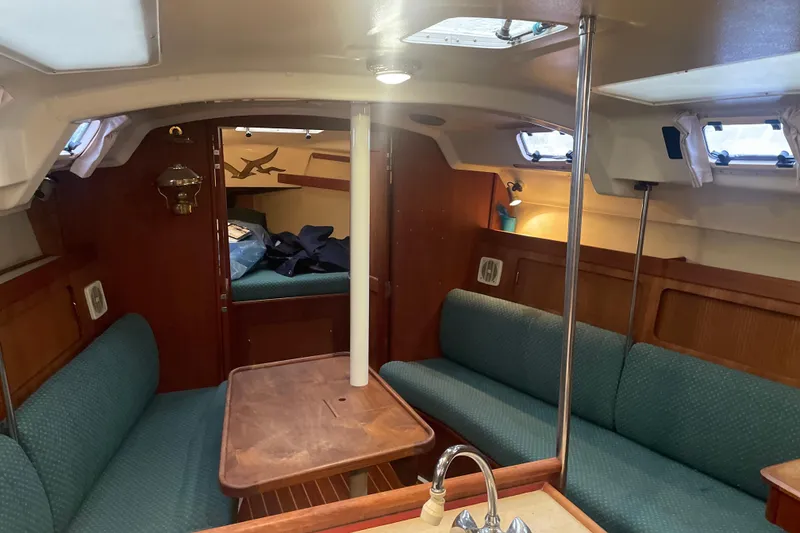 Slide: The Image of 1989 Hunter 35.5 sailboat interior with wood finish and teal seating. - 12