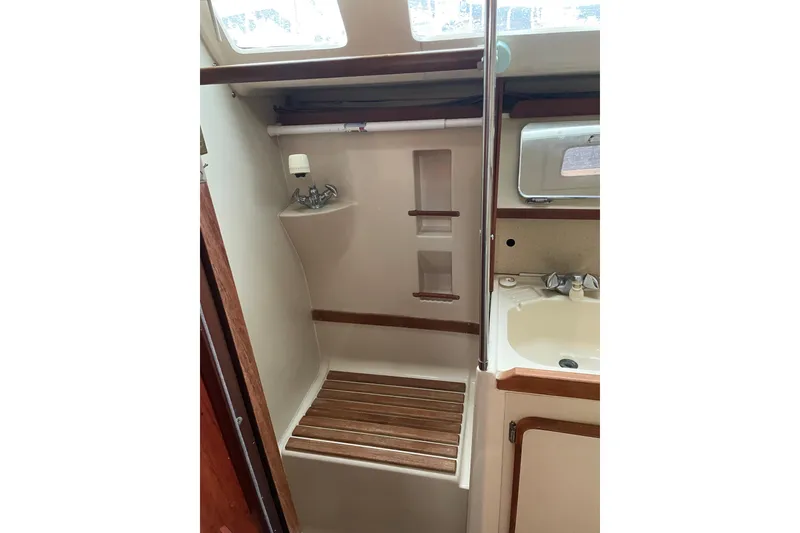 Slide: The Image of 1989 Hunter 35.5 yacht bathroom with shower and sink, featuring wooden accents. - 18