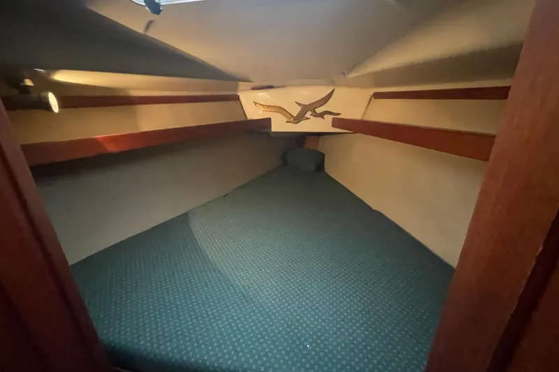 Slide: The Image of Cozy cabin interior of 1989 Hunter 35.5 sailboat with teal carpet and wooden shelves. - 27