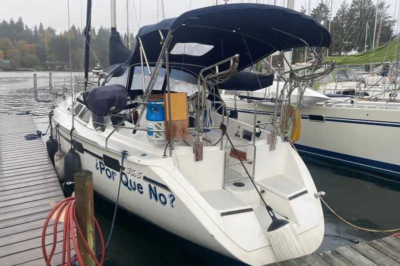 Slide: The Image of 1989 Hunter 35.5 sailboat docked, featuring a blue canopy and "¿Por Que No?" on the stern. - 3