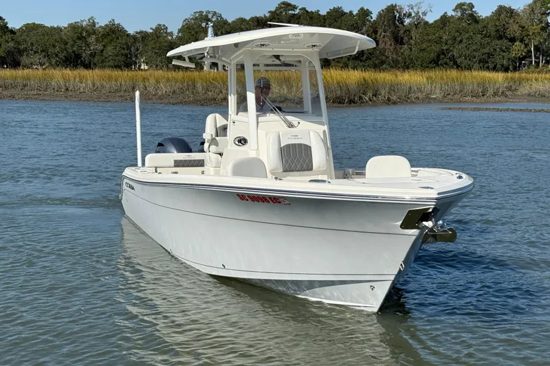Slide: The Image of 2023 Cobia 240CC boat cruising on a calm river with lush greenery in the background. - 10