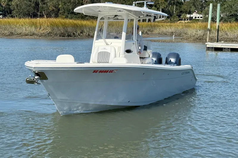 Slide: The Image of 2023 Cobia 240CC boat on calm water, featuring dual engines and sleek design. - 12