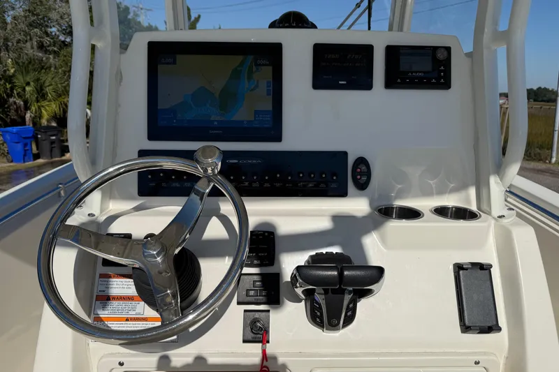Slide: The Image of 2023 Cobia 240CC boat dashboard with steering wheel, navigation screen, and controls. - 15