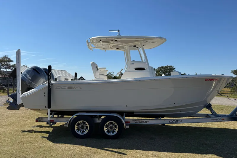 Slide: The Image of 2023 Cobia 240CC boat on trailer with Yamaha engine, parked outdoors. - 2