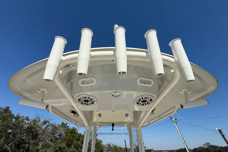 Slide: The Image of 2023 Cobia 240CC boat top view with rod holders and speakers against blue sky. - 34