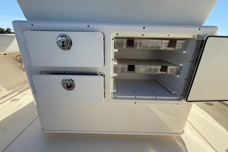 Slide: The Image of 2023 Cobia 240CC boat storage compartments with open tackle box shelves. - 35