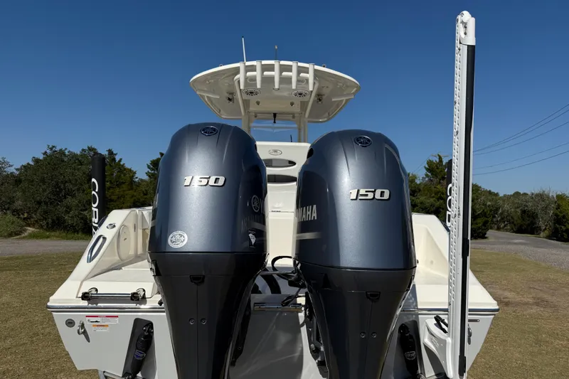 Slide: The Image of 2023 Cobia 240CC boat with dual Yamaha 150 engines, parked on grass. - 5