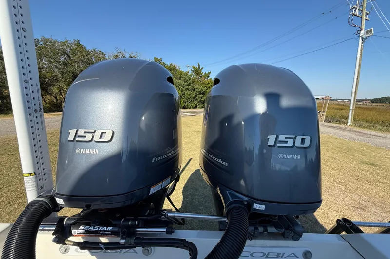 Slide: The Image of Twin Yamaha 150 outboard engines on a 2023 Cobia 240CC boat, parked outdoors. - 8