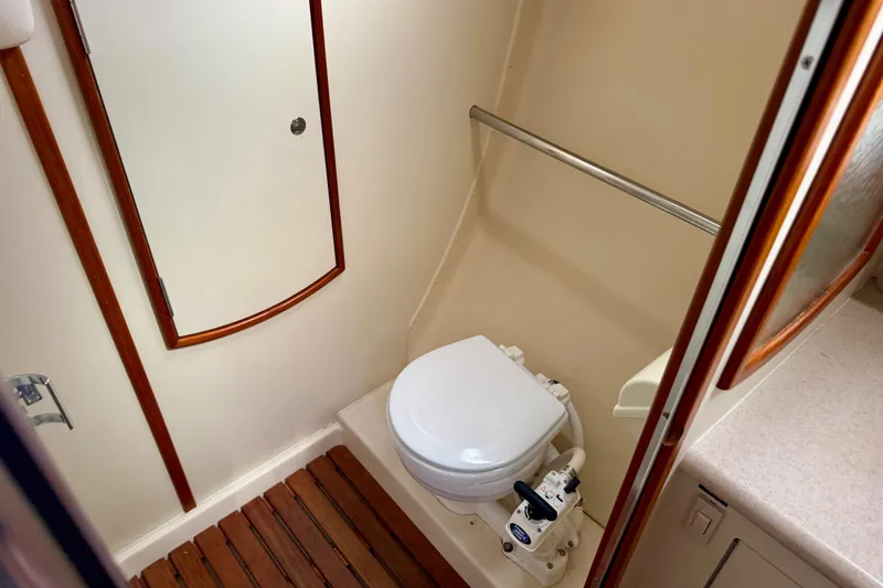 Slide: The Image of 2003 Hunter 36 yacht bathroom with toilet, wooden floor, and storage cabinet. - 16