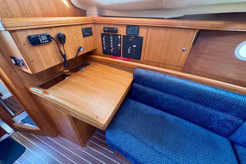 Slide: The Image of Interior of 2003 Hunter 36 sailboat with navigation station and blue cushioned seating. - 8