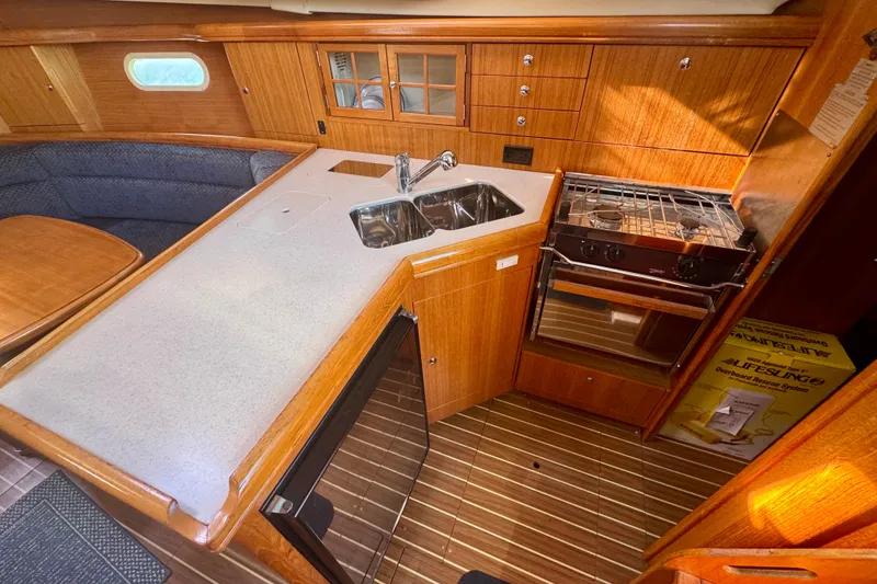 Slide: The Image of 2003 Hunter 36 yacht interior kitchen with wood cabinetry, sink, stove, and seating area. - 9